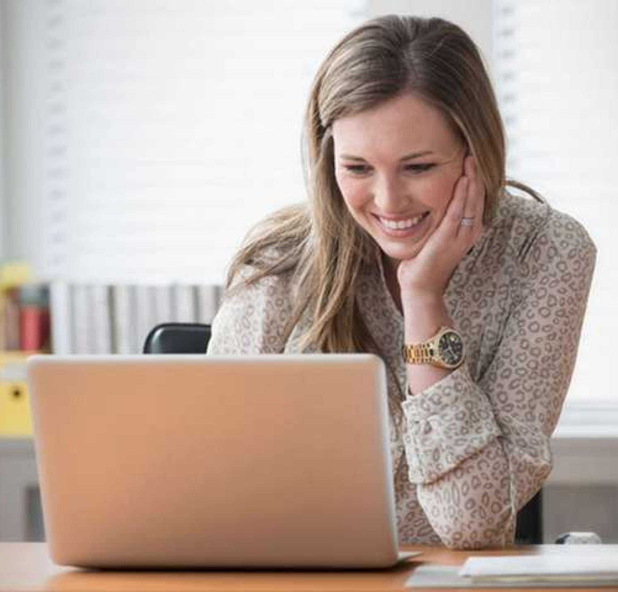 Une femme signe un document sur son ordinateur portable.